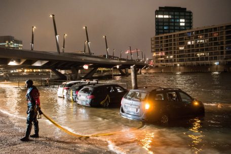 Autos stehen während der Sturmflut im Wasser der Elbe auf einem Parkplatz in der Hamburger HafenCity und werden von einem Feuerwehrmann gesichert
