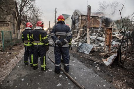 Feuerwehrleute betrachten in Kiew am 25.2. die Trümmer eines Flugzeugs das zwischen Häusern abgestürzt ist. Es war unklar, wessen Flugzeug abgestürzt ist und wer es zum Absturz gebracht hat.