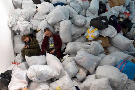Freiwillige Helfer ruhen sich in Lwiw auf den Säcken einer Kleidersammlung aus
