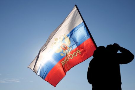 „Ihr wisst, wie ich denke“, sagt Vucic: In Belgrad hält ein Mann eine russische Fahne während einer Kundgebung zur Unterstützung Russlands