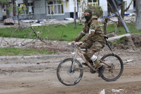 04.05.2022, Ukraine, Mariupol: Ein Angehöriger der Miliz der Volksrepublik Donezk fährt in Mariupol, einem Gebiet unter der Regierung der Volksrepublik Donezk in der Ostukraine, auf einem Fahrrad