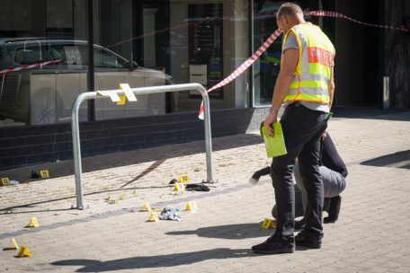 Beamte der Spurensicherung arbeiten auf dem Platz vor einem Hochhaus in der hessischen Stadt Hanau
