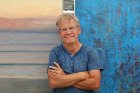 Der Maler Arne Henning vor seinen Gemälden