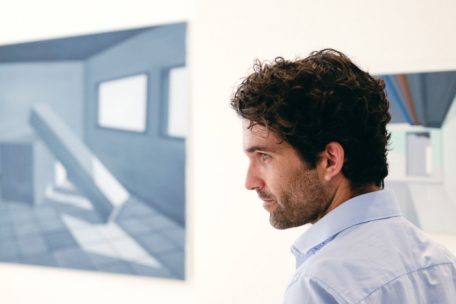 S&eacute;bastien Mettraux devant des peintures appartenant &agrave; la s&eacute;rie &bdquo;Dernier paysage I&ldquo;