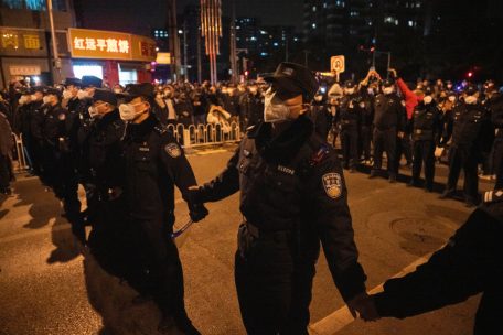 27.11.2022, China, Peking: Polizisten bilden eine Linie, um Demonstranten zu stoppen