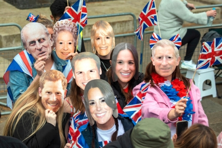 Zuschauer mit königlichen Masken stehen vor der Krönungszeremonie von König Charles III. und Königin Camilla im Zentrum Londons