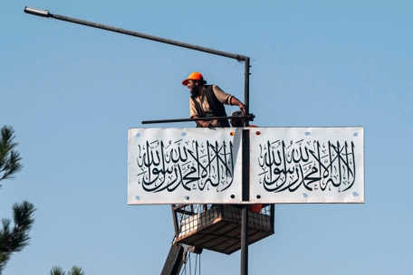 Ein afghanischer Arbeiter hängt am 13. August 2023 eine Taliban-Flagge in einer Straße in Kabul auf.
