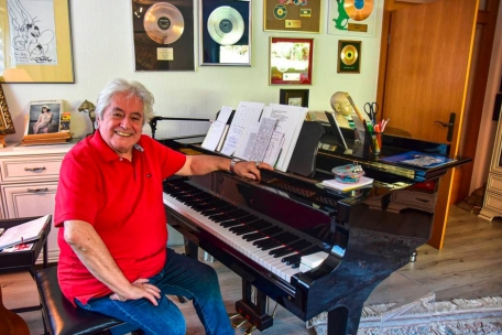 Metty Krings am Klavier in seiner Wohnung in Trier – im Hintergrund: Gold- und Platinalben sowie eine Original-Zeichnung von Asterix-Legende Uderzo