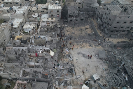 Palästinenser gehen am 29.10. im Flüchtlingslager Nusseirat im Gazastreifen um Gebäude herum, die durch israelischen Beschuss zerstört wurden.