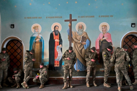 Ukrainische Soldaten blicken auf ihre Smartphones, während sie inmitten der russischen Invasion in der Ukraine am 1. November 2023 neben den Fresken in der St. Michaels-Kathedrale in Kiew stehen und sich vor dem Herbstregen schützen.