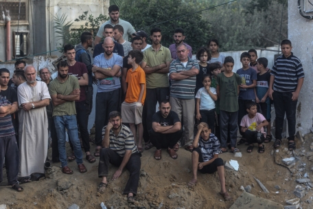 Palästinenser stehen an einem Krater von einem zerstörten Gebäude, der durch einen israelischen Angriff verursacht wurde