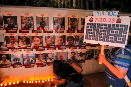 Menschen zünden vor dem israelischen Parlament (Knesset) in Jerualem  Kerzen unter einer Wand an, auf der Plakate mit den Namen der Geiseln zu sehen sind, die während des Angriffs vom 7. Oktober von militanten Palästinensern entführt wurden und derzeit im Gazastreifen festgehalten werden.
