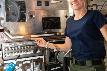 Astronautin Loral O’Hara posiert vor der Maschine zur Glasfaserprodution 