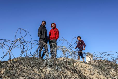 03.08.2024, Palästinensische Gebiete, Rafah: Vertriebene Palästinenser stehen hinter Stacheldraht vor ihren Zelten in der Nähe der ägyptischen Grenze im südlichen Gazastreifen.  Aufgrund des Angriffs der israelischen Armee flohen Palästinenser aus Beit Lahia, Jabalia, Gaza-Stadt und Chan Junis in die Stadt Rafah. Foto: Abed Rahim Khatib/dpa +++ dpa-Bildfunk +++