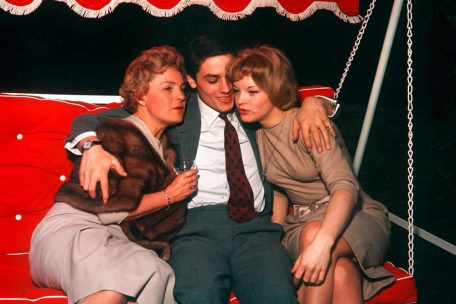 Alain Delon sitzt auf einer Hollywoodschaukel zwischen seiner damaligen Verlobten Romy Schneider (r) und deren Mutter Magda Schneider (l)