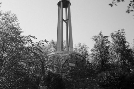 Im Turm, der aus vier sich verjüngenden Greyträgern besteht, hängt eine bronzene Glocke