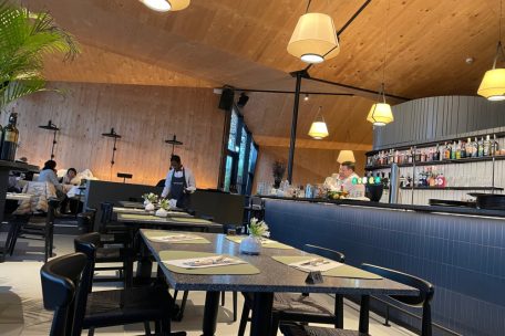 Das Innendesign kombiniert warme Holzelemente mit poliertem Beton und einem markanten blauen Fliesen-Counter