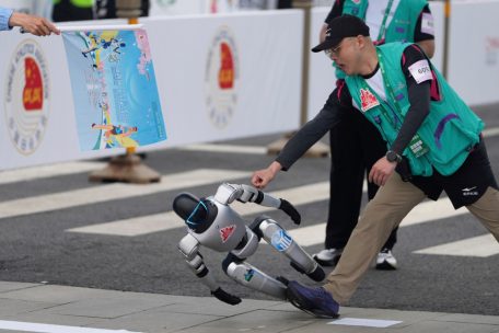 Ein Roboter verliert beim Start des Roboter-Halbmarathons die Kontrolle und muss von einem Mitarbeiter aufgefangen werden.