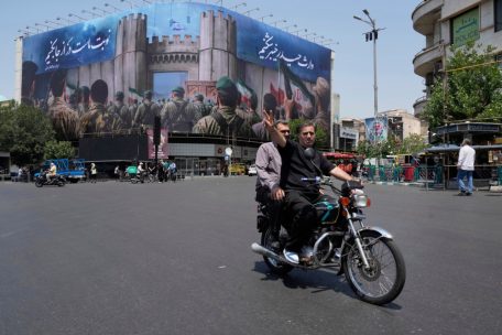 Platz der Islamischen Revolution in Teheran: Ein Mann zeigt ein Siegeszeichen, während er mit seinem Motorrad an einem anti-israelischen Banner vorbeifährt, auf dem iranische Soldaten abgebildet sind, die angeblich auf dem Weg sind, israelisches Gebiet anzugreifen