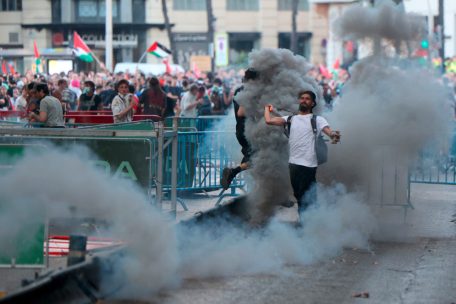 Ein Mann wirft eine Rauchfackel, nachdem pro-palästinensische Demonstranten während der 21. und letzten Etappe in Madrid auf die Straße gestürmt sind