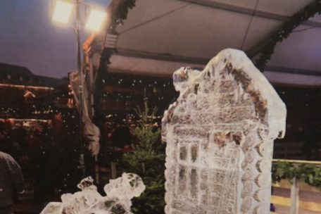 Auf dem aus Eis geformten Schlitten im Vordergrund liegt ein Fell, auf den sich Menschen setzen k&ouml;nnen, um Fotos zu machen. Dahinter ist der Teil der Skulptur zu sehen, die auf den zweij&auml;hrigen Emran fiel. Dieser stellt eine Holzchalet-Fassade dar.