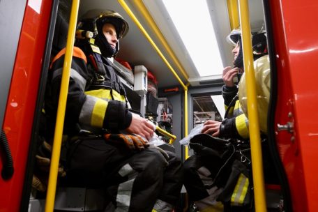 Feuerwerk trotz Verbot am Nachthimmel, Einsatzkräfte in Schutzkleidung bereit für Notfälle